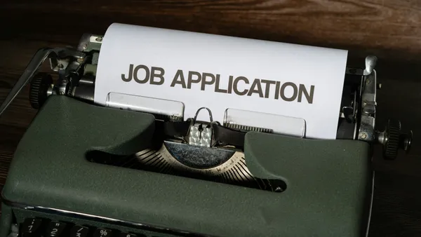 A green typewriter with a job application printed on it