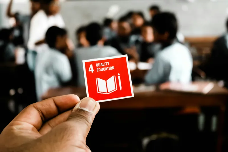 A photo of a hand holding a SDG4 Quality Education red sticker